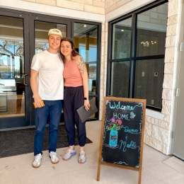 a couple posing for a picture next to a sign