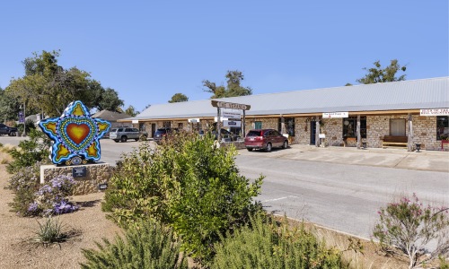 a storefront of shops and boutiques with a Dripping Springs star